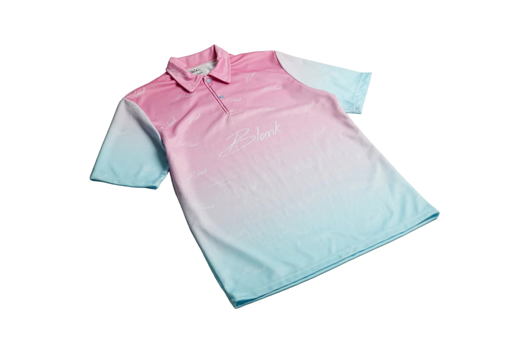 A short-sleeve polo shirt with a pink-to-light-blue gradient, laid flat on a light gray surface. The shirt features a white script logo on the chest and subtle white text patterns throughout.